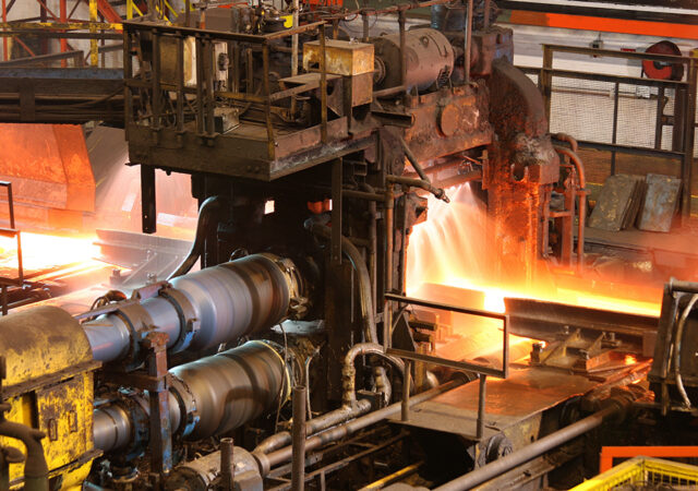Hot steel being rolled to shape in mill in steel manufacturing p