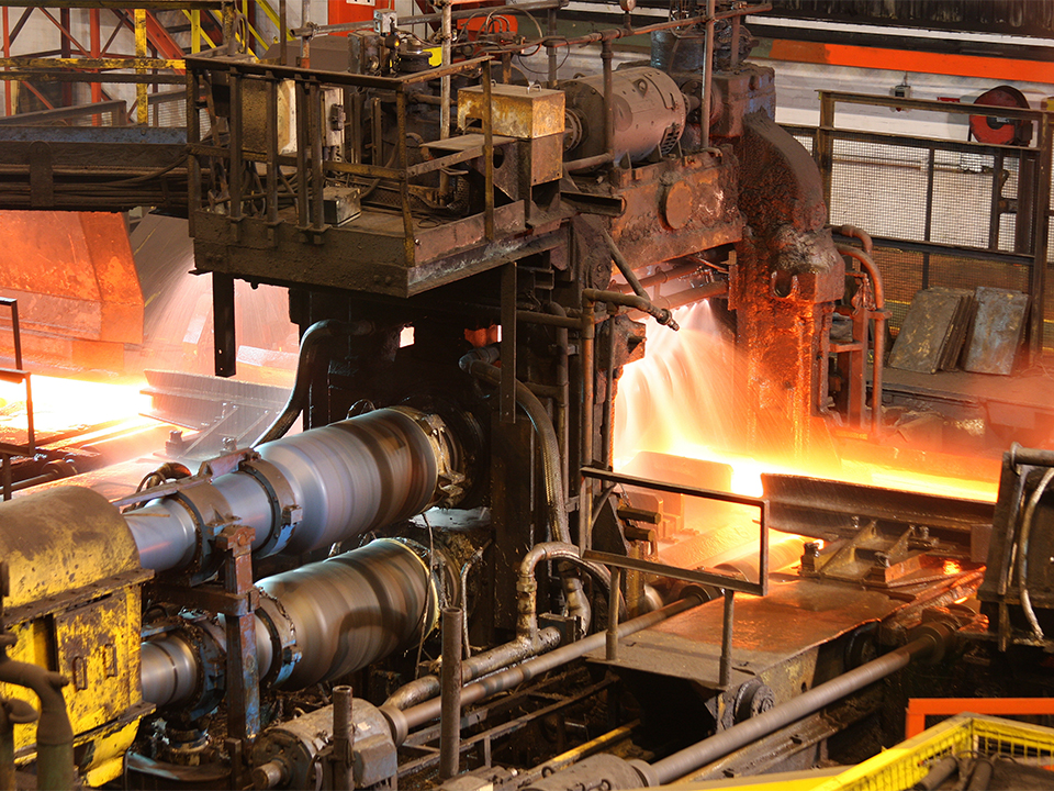 Hot steel being rolled to shape in mill in steel manufacturing p